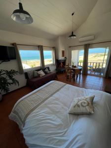 een slaapkamer met een wit bed en uitzicht op de oceaan bij El Diablo Chic Colonial in Punta Del Diablo