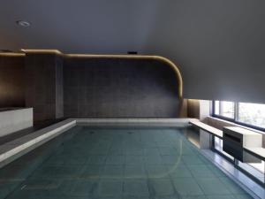 a swimming pool in a room with a window at SOKI Kanazawa in Kanazawa