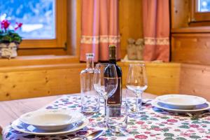 a table with a bottle of wine and two glasses at Cesa Valeria App Monika in Ortisei