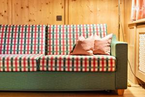 a green plaid couch with two pillows on it at Cesa Valeria App Monika in Ortisei