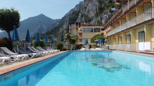 una piscina dell'hotel con sedie e montagne sullo sfondo di Hotel Splendid Palace a Limone sul Garda