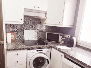 a kitchen with a washing machine and a microwave at www apartamentovaldivia es Parking incluido in León