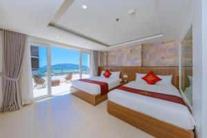 two beds in a room with a view of the ocean at Dubai Nha Trang Hotel managed by HT in Nha Trang