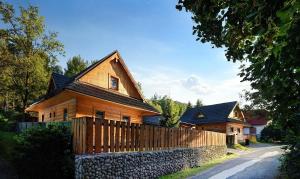 uma casa de madeira com uma cerca ao lado de uma estrada em Chalupa Goral em Jezersko