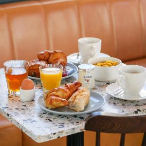 uma mesa de pequeno-almoço com croissants, café e sumo de laranja em Eklo Lyon em Vénissieux