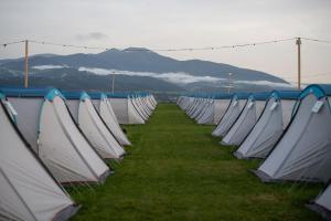 Une rangée de tentes blanches bordées d'herbe dans l'établissement GPtents- Spielberg, à Spielberg