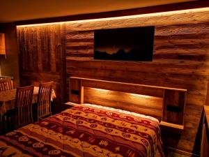 a bedroom with a log wall with a bed and a television at Residence Petit Tibet in Breuil-Cervinia