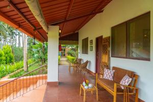 a porch of a house with a bench and a table at StayVista at Firefly By The River with Breakfast in Kushālnagar