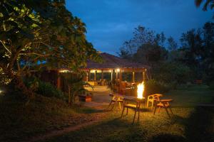 a table and chairs in front of a building at night at StayVista at Firefly By The River with Breakfast in Kushālnagar