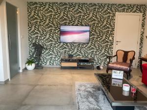 a living room with a tv on a wall at Lovely 1-bedroom appartement Le Joyau with indoor pool and sauna in Lasne