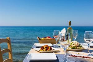 a table with wine glasses and food on the beach at Theo Star Beach Hotel in Malia