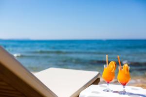 two glasses of orange juice sitting on a table near the ocean at Theo Star Beach Hotel in Malia