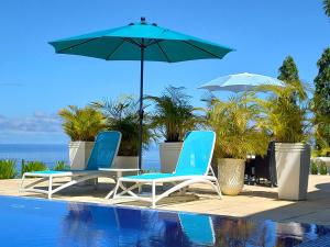 two chairs and an umbrella next to a swimming pool at Petit Amour Villa, Seychelles in Victoria