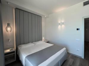 een witte slaapkamer met een groot wit bed en verlichting bij Hotel Rex in Livorno