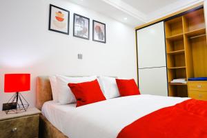 Schlafzimmer mit einem Bett mit roten und weißen Kissen in der Unterkunft Elite Luxury Apartments Kilimani - A 2 Bedroom Oasis of Serenity in Nairobi