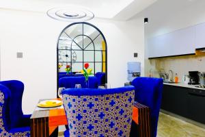 ein Esszimmer mit blauen Stühlen und einem Tisch sowie eine Küche in der Unterkunft Elite Luxury Apartments Kilimani - A 2 Bedroom Oasis of Serenity in Nairobi