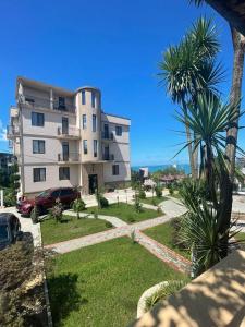 a large apartment building with palm trees in front of it at Green Yard Hotel in Batumi