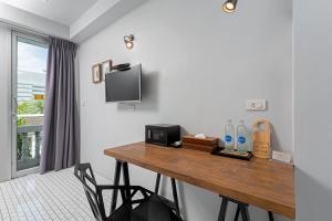 a room with a wooden table with a microwave and a television at Hip Hostel - SHA Plus in Patong Beach