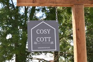 een teken dat zegt dat cozyct aan een ketting hangt bij Cosy Cott, een verborgen logeerplek in het landelijke Poeke. in Aalter