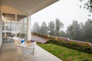 eine Terrasse mit Stühlen und Gartenblick in der Unterkunft StayVista at The Lilly Ooty with Breakfast in Udagamandalam