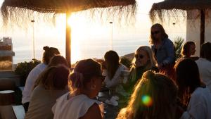 Un groupe de personnes assises autour d'une table au coucher du soleil dans l'établissement The Salty Pelican Yoga & Surf Retreat, à Ericeira