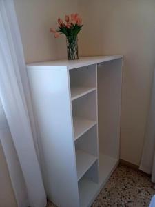 a white shelf with a vase of flowers on it at Big apartment on the beach in Tolo