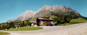 um edifício ao lado de uma montanha com uma estrada em Gästehaus Gschwandtner em Mühlbach am Hochkönig