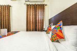 een slaapkamer met een bed met witte lakens en kussens bij FabHotel RMS Comforts - Nr Yeshwantpur Railway Station in Bangalore