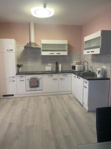 a large kitchen with white cabinets and appliances at Privatzimmer Hammrich in Neudörfl