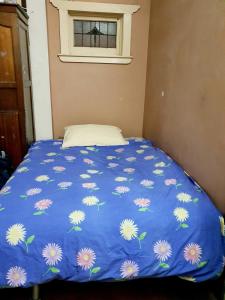 een bed met een blauw dekbed met bloemen erop bij St Kilda East backpackers' hostel in Melbourne