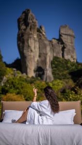 a woman laying on a bed in front of a mountain at Pyrgos Adrachti in Kalabaka