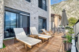 a deck with chairs and an umbrella on a building at Beachfront Villa Nautica in Kotor