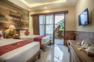 a hotel room with two beds and a television at Merak Village by Prasi in Ubud