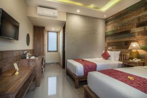 a hotel room with two beds and a television at Merak Village by Prasi in Ubud