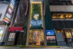 un bâtiment avec un panneau à l'avant dans l'établissement Petit Bali Forest Shinjuku Sanchōme, à Tokyo