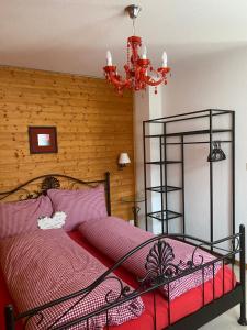 1 dormitorio con cama roja y lámpara de araña en Ferienwohnung Allalinblick, en Saas-Fee