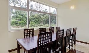 - une salle à manger avec une table et des chaises en bois dans l'établissement Treebo Aall Season, à Kodaikānāl