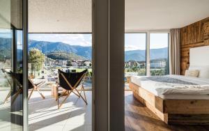 una camera con letto e un balcone con vista sulle montagne di Bellevue Bruneck - Suites & Lofts a Brunico