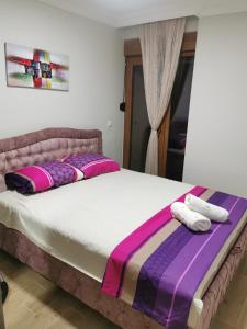 um quarto com uma cama grande com almofadas roxas e cor-de-rosa em Apartman DalMe em Novi Pazar