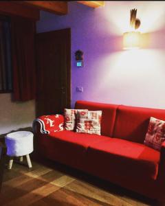 sala de estar con sofá rojo y almohadas en Casa Romeo, en San Vito di Cadore