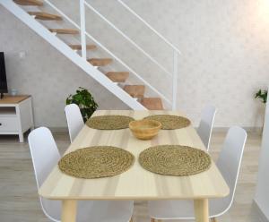 una mesa de comedor con sillas blancas y una escalera blanca en Loft Sol y Luna en Las Palmas de Gran Canaria, en Las Palmas de Gran Canaria