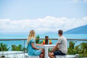 um homem e uma mulher sentados numa mesa numa varanda em Freedom Shores Resort Airlie Beach em Airlie Beach