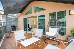 a porch with white chairs and a swing at Villa Franco Pet Friendly 10 Mins Walk to Beach in Surf Beach