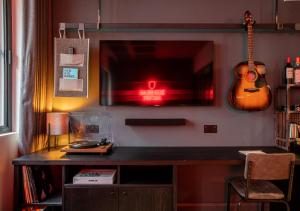 een bureau met een tv en een gitaar aan de muur bij BrewDog DogHouse Manchester in Manchester