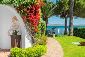 un jardín con flores rojas en una pared blanca en The Pelican Beach Resort & SPA - Adults Only, en Olbia