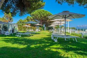 un grupo de mesas de picnic con sombrillas en la hierba en The Pelican Beach Resort & SPA - Adults Only, en Olbia