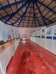 um quarto vazio com piso vermelho e pinturas nas paredes em Il Triangolo Hostel em Las Galeras