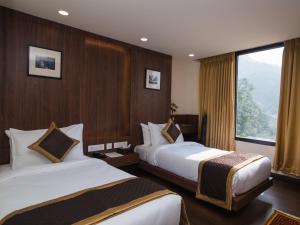 a hotel room with two beds and a window at Tree of Life Indra Mandala Hotel, Gangtok in Gangtok