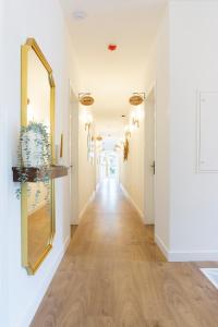 un long couloir avec des murs blancs et un miroir dans l'établissement Lugar do Ourives Boutique Hotel, à Senhora das Febres