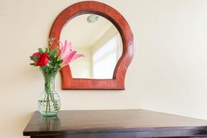 un jarrón de flores sobre una mesa con un espejo en Hotel las flores, en Santa Cruz Huatulco